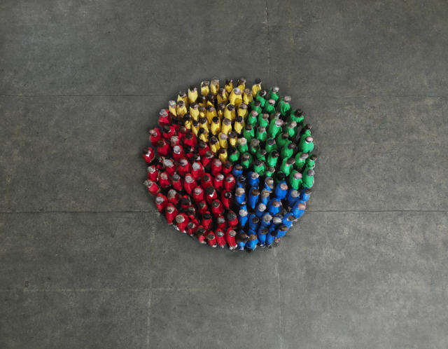 A crowd of people wearing red, yellow, green and blue coloured shirts, forming a pie chart shape; fractional hiring for startups, hiring contractors