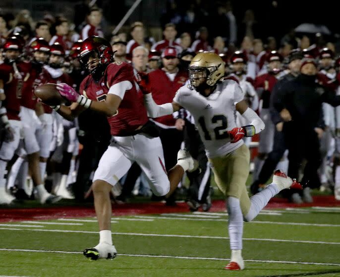 DOWNEY, CALIF. - DEC. 2, 2022. Downey receiver Byrant Carey catches a pass en route to then zone against Mater Dei Catholic defensive back Evan Isidro in the firts quarter of the State Division 2-AA football playoff game in Downey on Friday night, Dec. 2, 2022. High School. (Luis Sinco / Los Angeles Times)