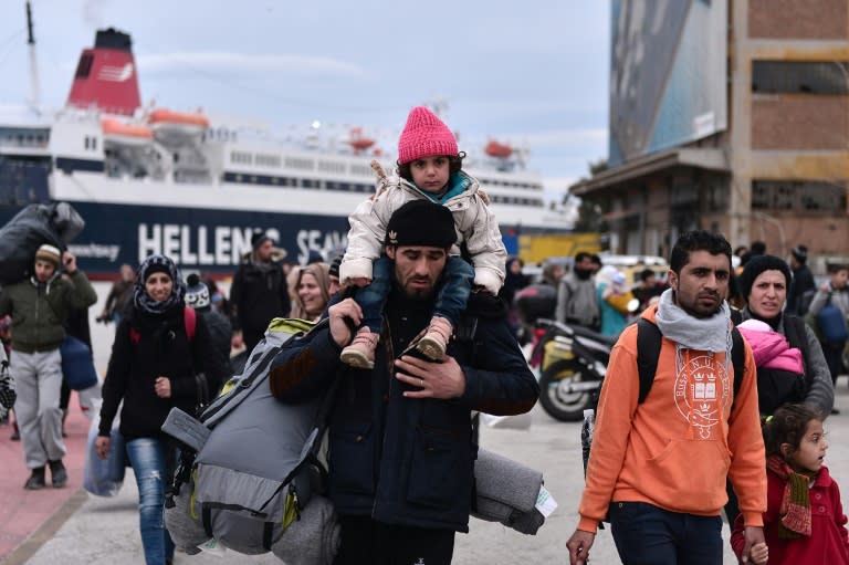 Migrants walk through the port of Piraeus near Athens on their arrival from the island of Lesbos on February 10, 2016