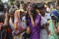 Relatives mourn as villagers gather around the bodies of victims of a road accident in Kanpur, Uttar Pradesh state, India, Sunday, Oct.2, 2022. A farm tractor pulling a wagon loaded with people overturned and fell into a pond in Kanpur city's Ghatampur area Saturday night killing 26 people, most of them women and children. (AP Photo)