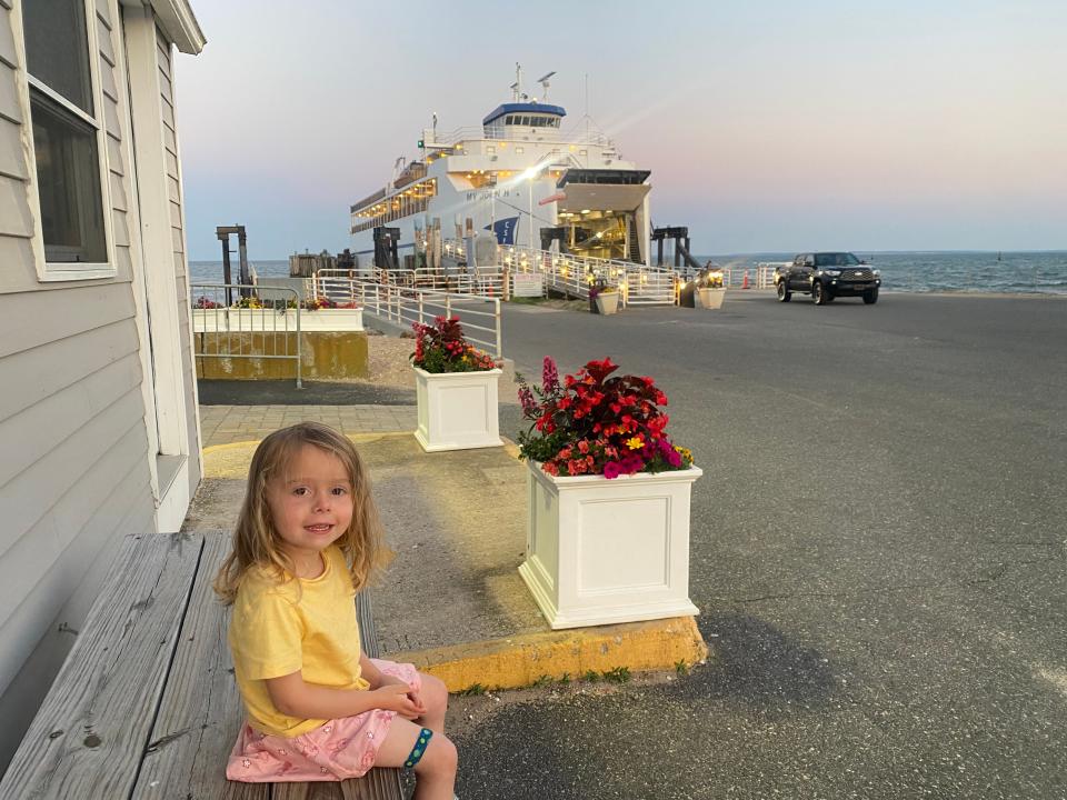child sitting on a bench outside near a ferry dock
