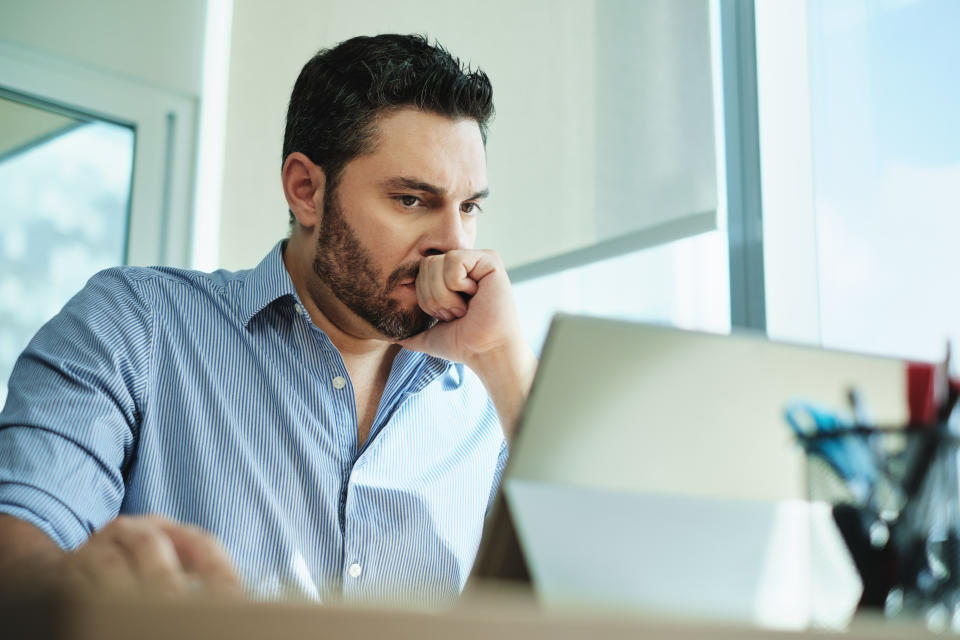 Angry Hispanic businessman working with laptop computer in office, losing patience. Anxious executive man under stress at work for technology problems and software pc virus.