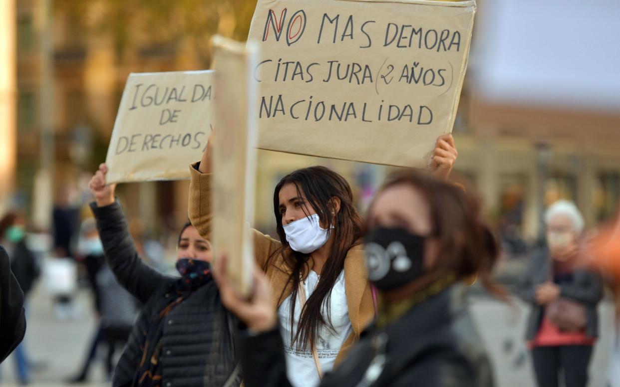 Demonstrators hold placards during a protest demanding "papers, rights, nationality and social equality" for undocumented immigrants in Barcelona - Pau Barrena/AFP