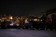 People sit on a roof to watch a movie projected on a giant screen in the low-income neighborhood of Petare, amid the coronavirus disease (COVID-19) outbreak in Caracas