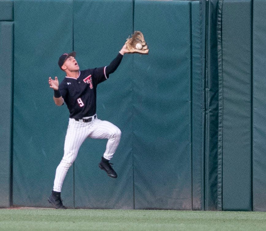 Texas Tech right fielder Zac Vooletich pulls in a drive by Florida's Wyatt Langford just before he runs into the right-field wall in the third inning Sunday night. Florida beat Tech 7-1, forcing a game at 11 a.m. CDT Monday to determine the champion of the NCAA Gainesville Regional.