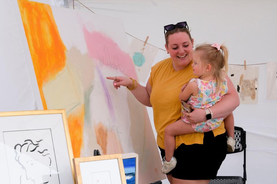 Sarah Beth Cotton holds Margaret Pruett as they look at paintings at the Druid City Arts Festival on March 31, 2023, in Government Plaza.