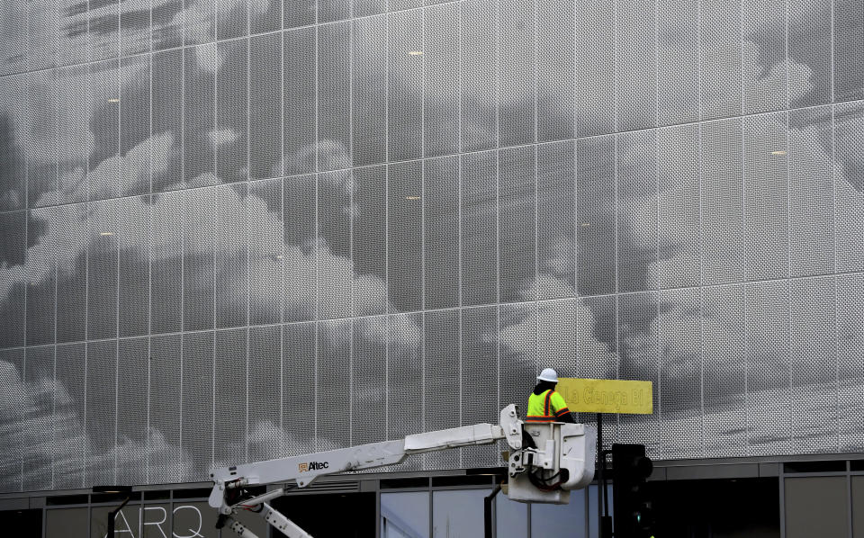 A construction worker works on the La Cienega Blvd. sign in front of the Cumulus District-Apartments in Los Angeles, Wednesday, Jan. 27, 2021. Wide areas of the state remained under warnings and watches for flooding, heavy snow and winds. (Keith Birmingham/The Orange County Register/SCNG via AP)