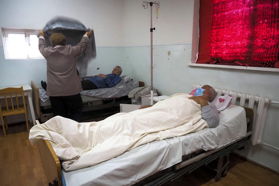 A woman covers her husband, who is suspected of having coronavirus, with a blanket in an infectious diseases clinic in Stepanakert, the separatist region of Nagorno-Karabakh, Tuesday, Oct. 20, 2020.Nagorno-Karabakh, which lies within Azerbaijan but has been under the control of ethnic Armenian forces since a war there ended in 1994, faces an outbreak of the coronavirus amid the largest outbreak of hostilities in more than a quarter-century. (AP Photo)