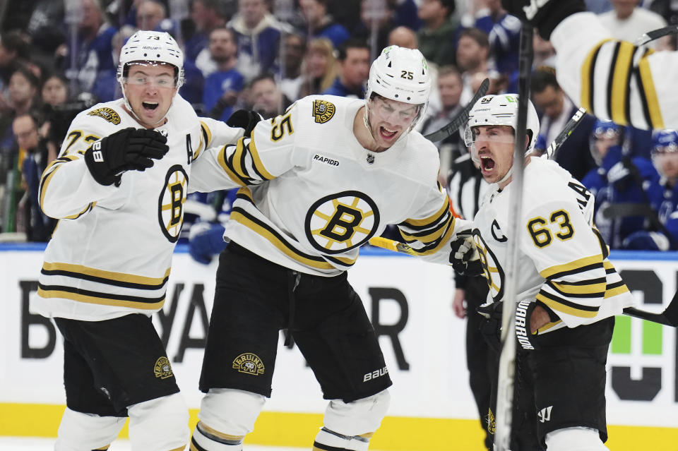 Boston Bruins' Brad Marchand (63) celebrates his goal against the Toronto Maple Leafs with Brandon Carlo and Charlie McAvoy during third period of action in Game 3 of an NHL hockey Stanley Cup first-round playoff series in Toronto on Wednesday, April 24, 2024. (Nathan Denette/The Canadian Press via AP)