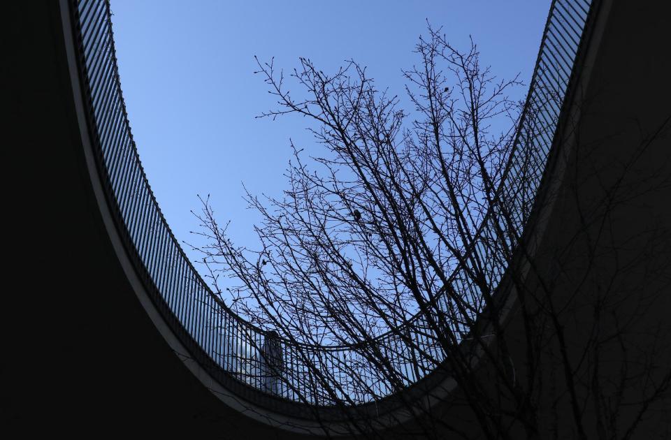 In this Thursday, Jan. 12, 2017 photo, a man walks past an open design feature of a building at Shinjuku district in Tokyo. Shinjuku is one of Tokyo's major commercial centers that houses Tokyo's Metropolitan Government building and the National Stadium that will be the main venue for the 2020 Summer Olympic games. (AP Photo/Shizuo Kambayashi, File)