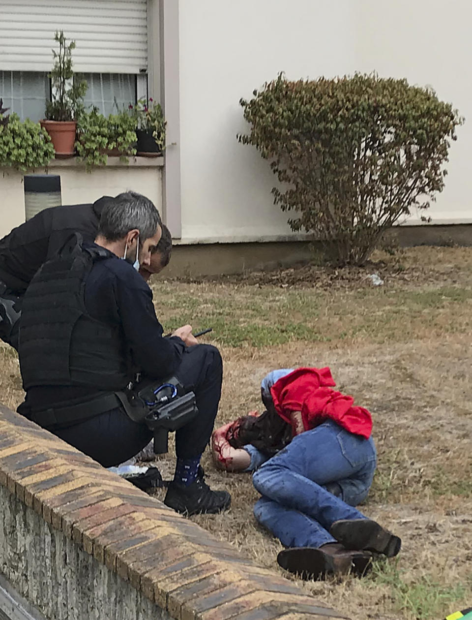A man is tended to after being injured in a knife attack in Paris, Friday, Sept. 25, 2020. French terrorism authorities are investigating the knife attack that wounded at least two people Friday near the former offices of the satirical newspaper Charlie Hebdo in Paris, authorities said. A suspect has been arrested. (David Cohen via AP)