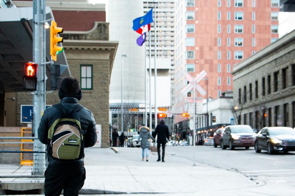 A pedestrian waits at a crosswalk in downtown Calgary on December 11, 2021. (Ose Irete/CBC)