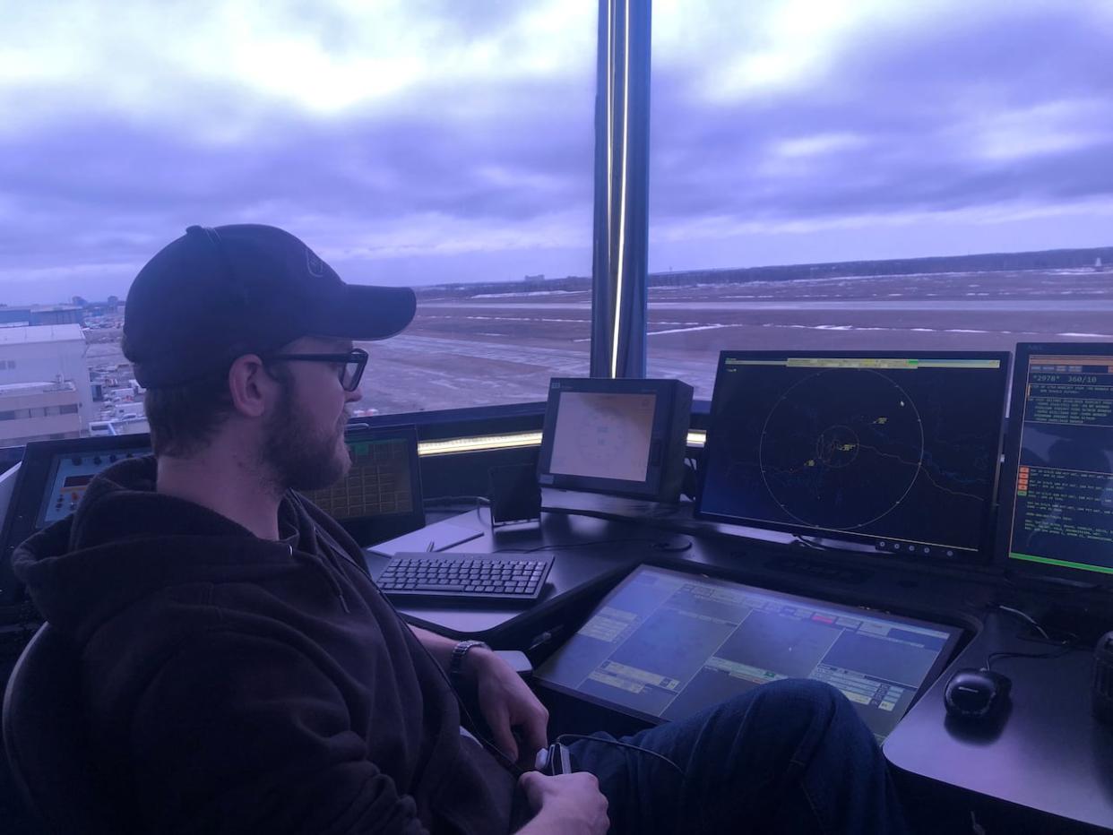 Air traffic controller Adam Plooy scans for planes in Yellowknife's control tower on April 25, 2024. (Sarah Krymalowski/CBC - image credit)