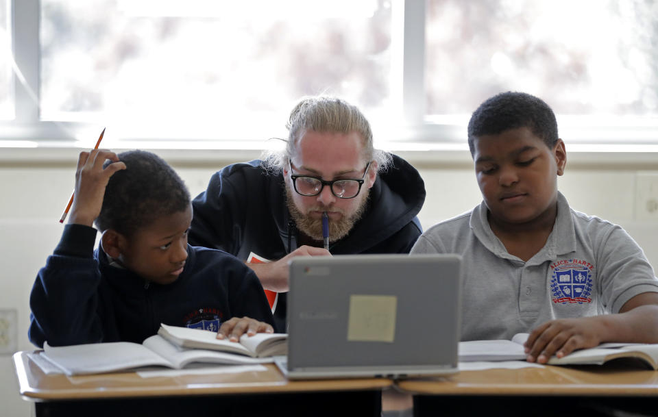 In this Tuesday, Dec. 18, 2018 photo, teacher Christian Mehalic, center, works with students Zion Odia, left, and Joryll Blain, at Alice M. Harte Charter School in New Orleans. Charter schools, which are publicly funded and privately operated, are often located in urban areas with large back populations, intended as alternatives to struggling city schools. (AP Photo/Gerald Herbert)