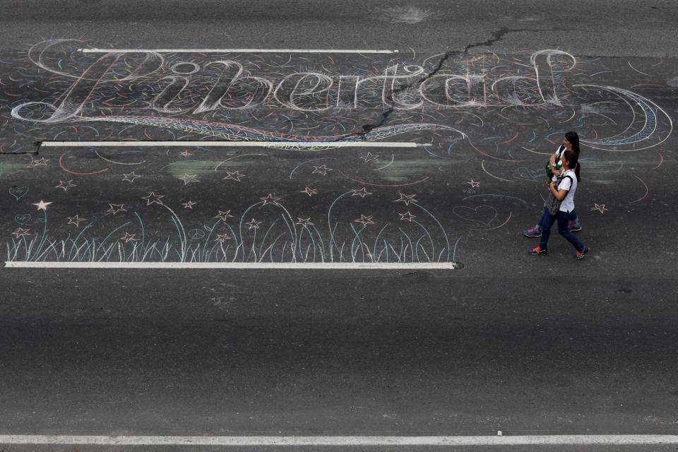 <p>Opposition supporters walk past a graffiti on the road that reads “Freedom”, during a protest against Venezuelan President Nicolas Maduro’s government in Caracas, Venezuela May 15, 2017. (Carlos Garcia Rawlins/Reuters) </p>