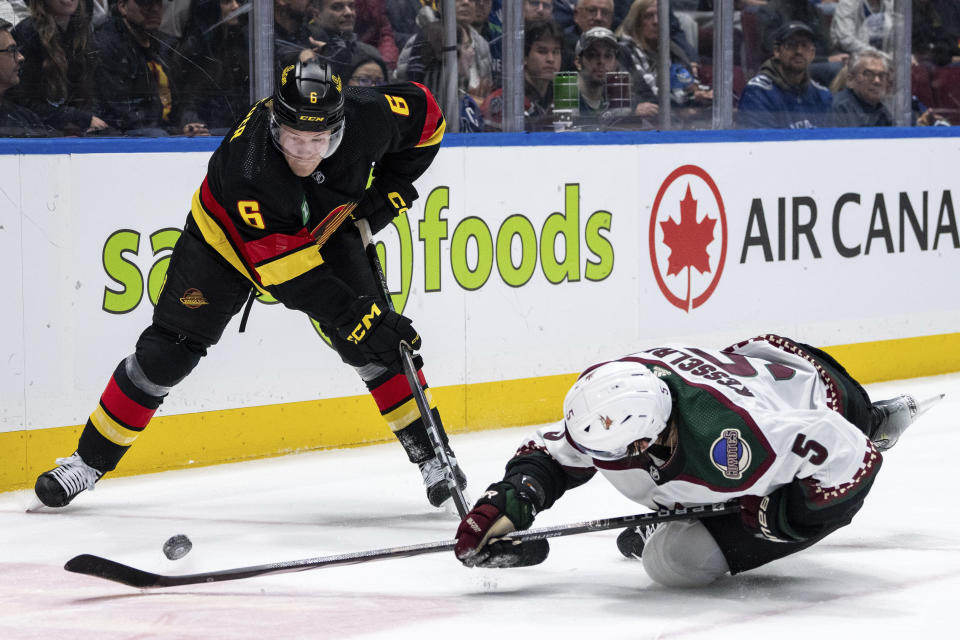 Vancouver Canucks' Brock Boeser (6) and Arizona Coyotes' Michael Kesselring (5) vie for the puck during the third period of an NHL hockey game Wednesday, April 10, 2024, in Vancouver, British Columbia. (Ethan Cairns/The Canadian Press via AP)