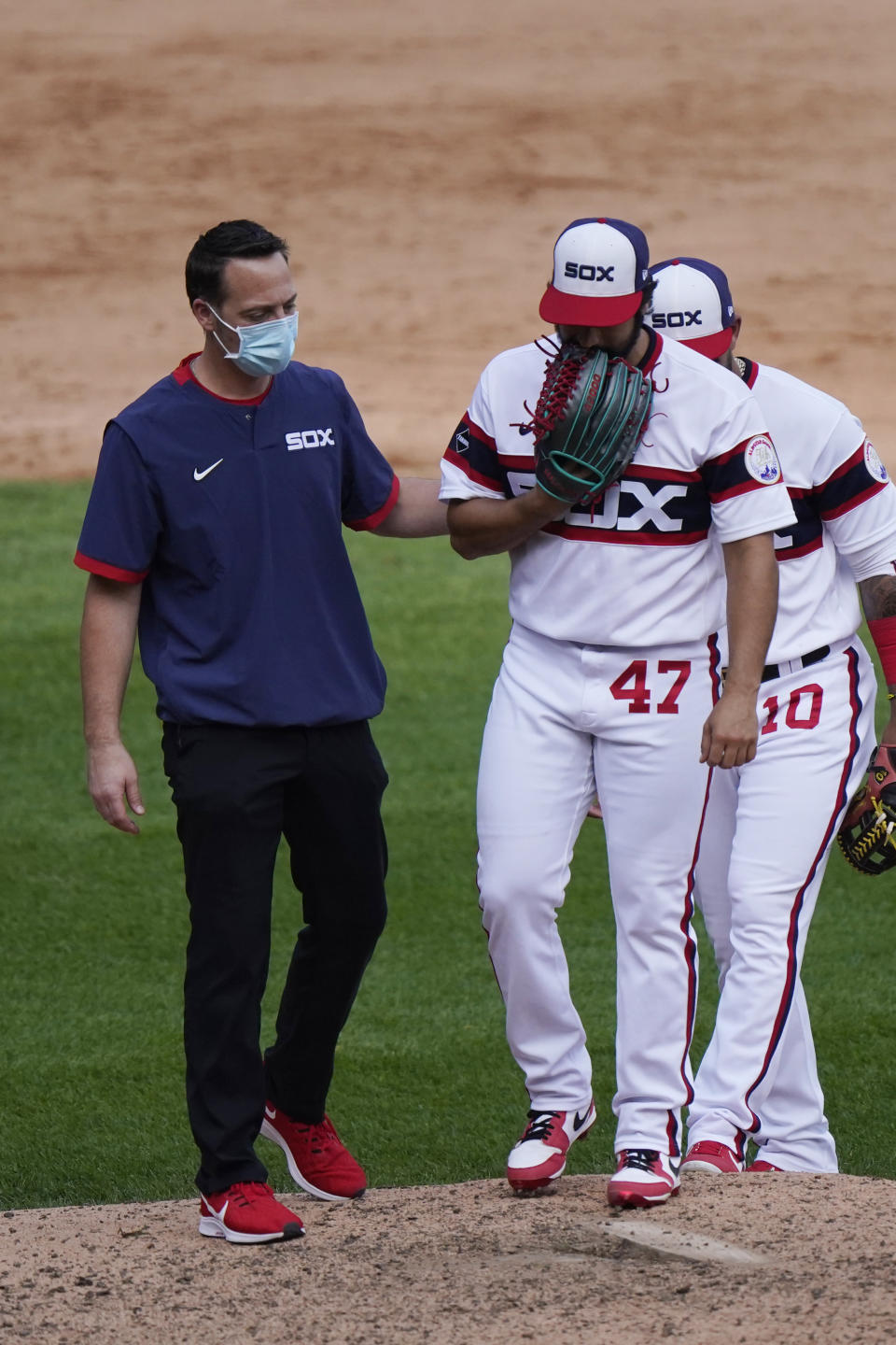 Chicago White Sox relief pitcher Gio Gonzalez, right, is checked by a team trainer after an injury during the seventh inning of a baseball game against the Chicago Cubs in Chicago, Sunday, Sept. 27, 2020. (AP Photo/Nam Y. Huh)