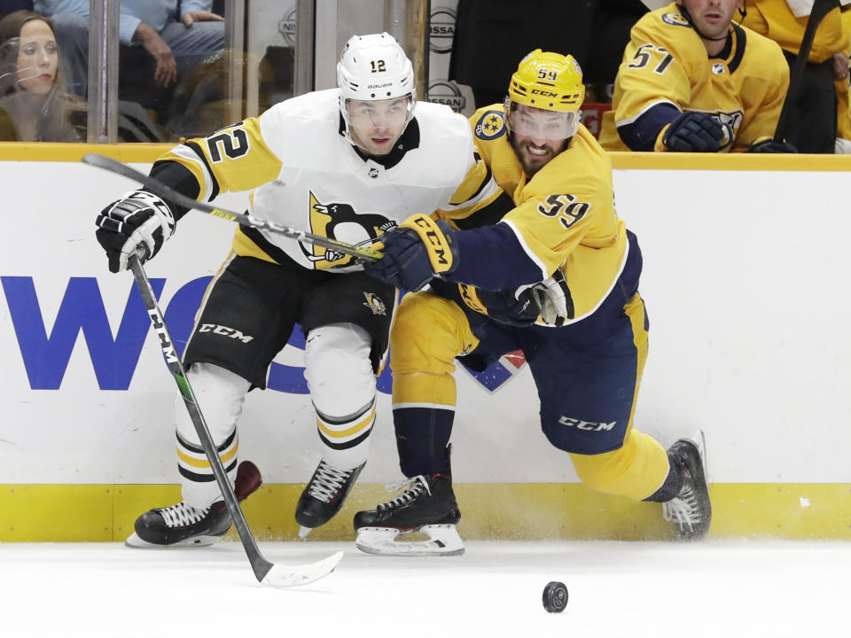 Pittsburgh Penguins center Dominik Simon (12), of the Czech Republic, and Nashville Predators defenseman Roman Josi (59), of Switzerland, compete for the puck during the third period of an NHL hockey game Friday, Dec. 27, 2019, in Nashville, Tenn. The Penguins won 5-2. (AP Photo/Mark Humphrey)