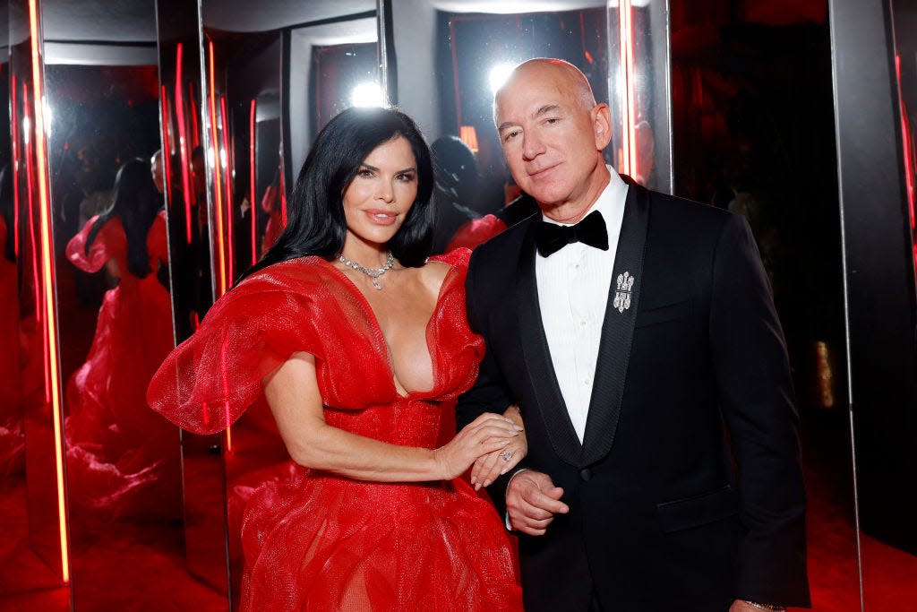 Lauren Sánchez and Jeff Bezos posing together at a black-tie event, with mirrors behind them.