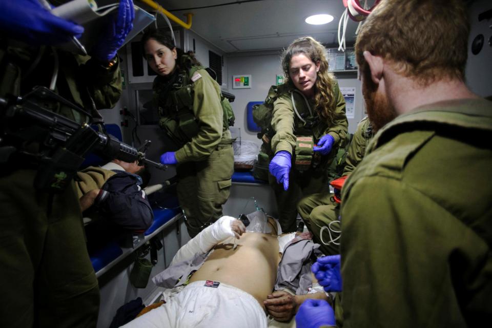 Israeli soldiers give initial medical treatment to wounded Syrians in the Israeli-occupied Golan Heights on 18 January 2017: REUTERS