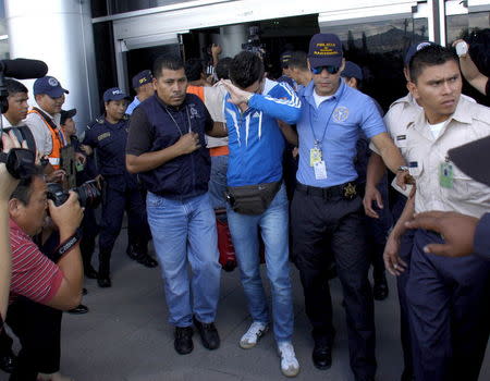 Policemen escort one of five Syrian men detained at Toncontin international airport in Tegucigalpa, Honduras, November 18, 2015. Honduran authorities have detained five Syrian nationals who were trying to reach the United States using stolen Greek passports, but there are no signs of any links to last week's attacks in Paris, police said. The Syrian men were held late on Tuesday in the Honduran capital, Tegucigalpa, on arrival from Costa Rica, and had been planning to head to the border with neighboring Guatemala. The passports had been doctored to replace the photographs with those of the Syrians, police said. REUTERS/Stringer EDITORIAL USE ONLY. NO RESALES. NO ARCHIVE.