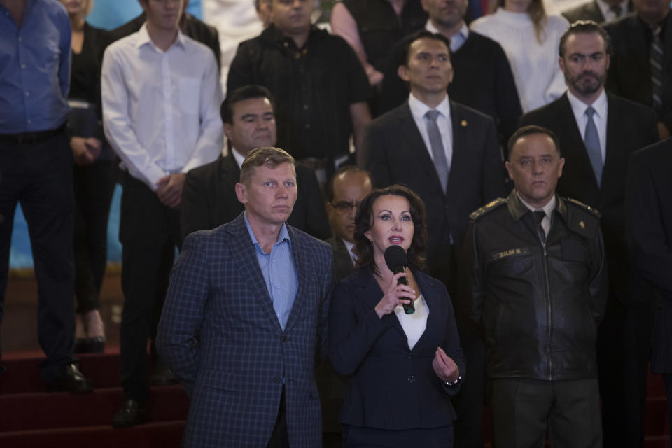 Irina Bitkova, center, and his husband Igor Bitkov, accused and convicted of corruption for the use of false documents to open businesses and buy property in Guatemala, thanked President Jimmy Morales for withdrawing from the commission, at the National Palace in Guatemala City, Monday, Jan. 7, 2019. Guatemala announced that it is going to withdraw from UN-sponsored anti-corruption commission. (AP Photo/Moises Castillo)