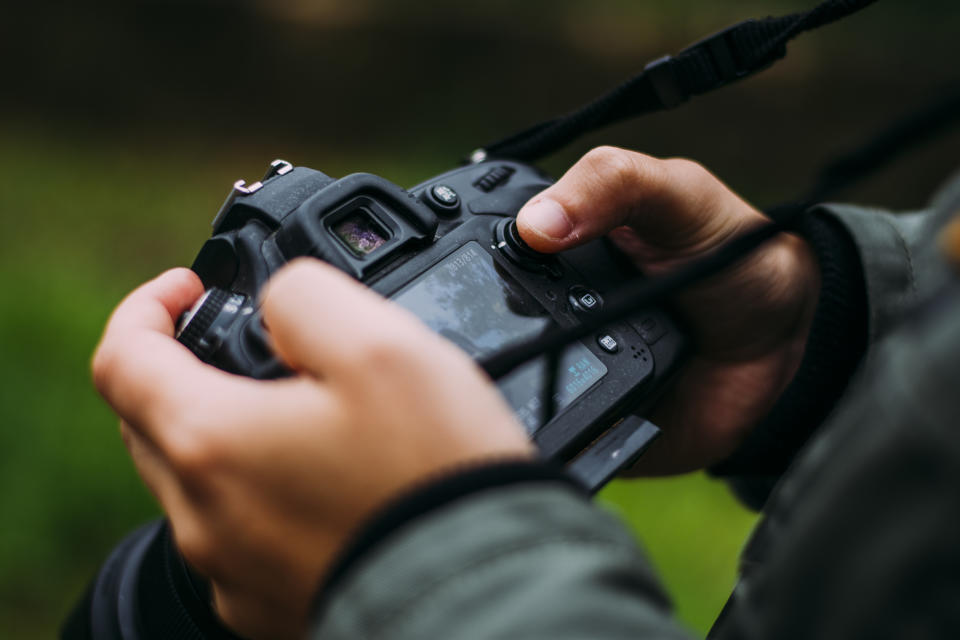 A stock photo of a young man holding a camera. Brisbane photographer Kye John Tanson has pleaded guilty to 60 child sex offences. 