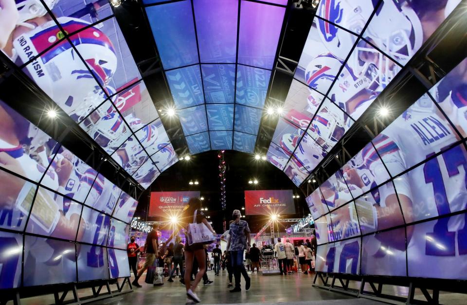 Fans walk though a tunnel of video monitors at the Super Bowl Experience.