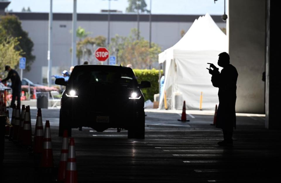 A healthcare worker instructs people how to take a self-administered mouth swab at a drive-through Covid-19 testing site in Redondo Beach, California