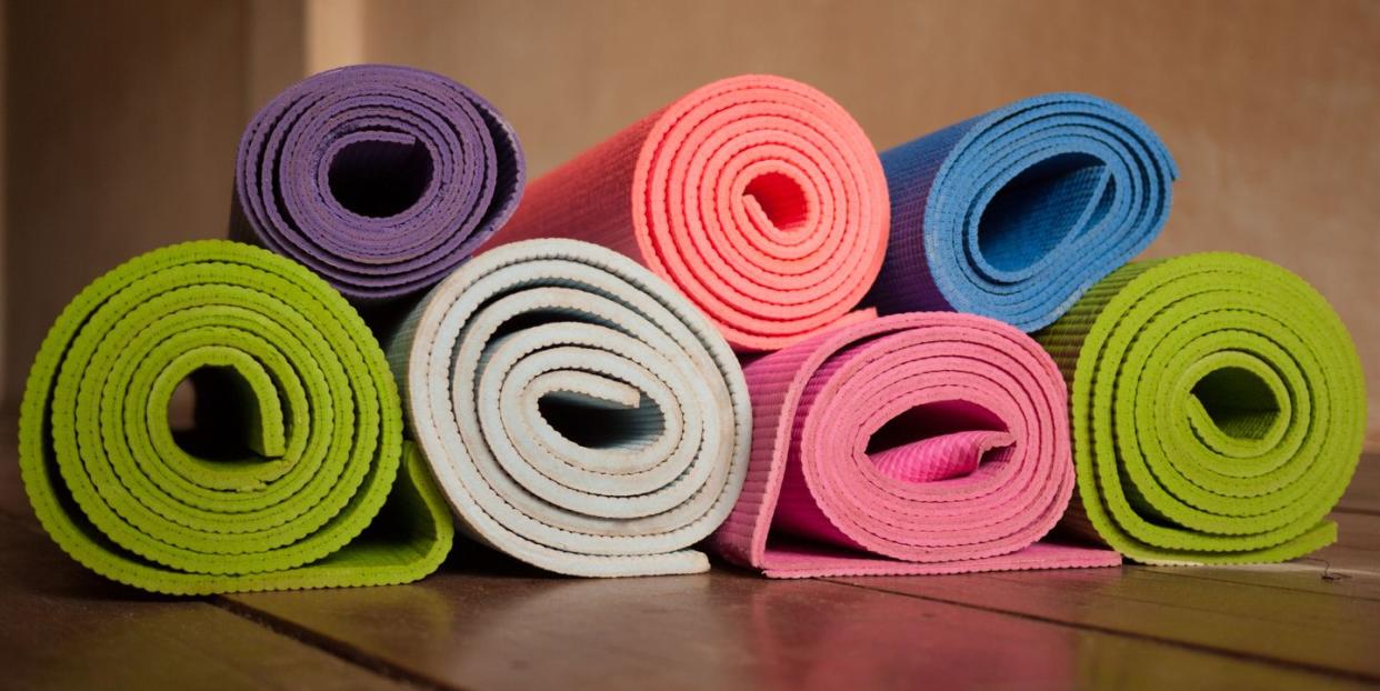 colorful yoga mats rolled up on a wooden floor in a yoga studio