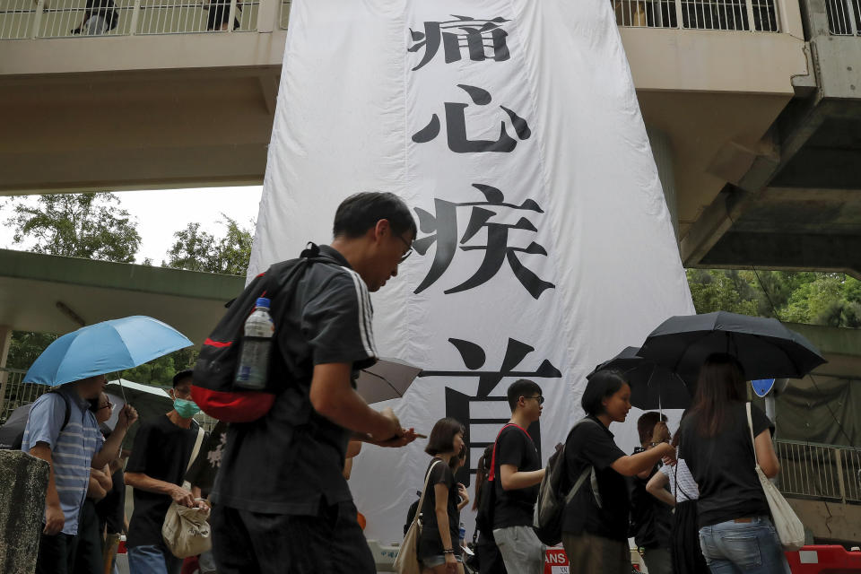 People walk past a banner which reads "Distressed" as they take part in the anti-extradition bill protest march in Hong Kong, Sunday, Aug. 4, 2019. The first of two planned protests in Hong Kong on Sunday has kicked off from a public park just hours after police said they arrested more than 20 people for unlawful assembly and other offences during the previous night's demonstrations. (AP Photo/Vincent Thian)