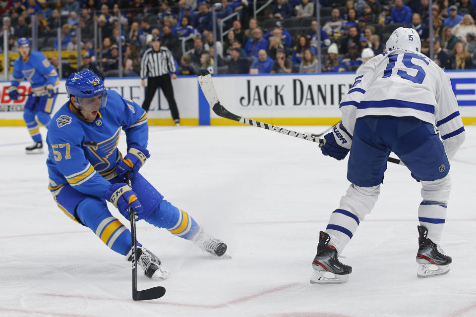 St. Louis Blues' David Perron, left, deflects a shot on a clearing attempt by Toronto Maple Leafs' Alexander Kerfoot during the second period of an NHL hockey game Saturday, Dec. 7, 2019, in St. Louis. (AP Photo/Billy Hurst)