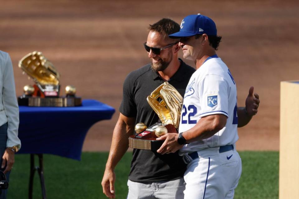 Former Kansas City Royals left fielder Alex Gordon, left, is presented his eighth Gold Glove by Royals manager Mike Matheny (22) during a ceremony before a baseball game against the Detroit Tigers at Kauffman Stadium in Kansas City, Mo., Saturday, July 24, 2021. (AP Photo/Colin E. Braley)