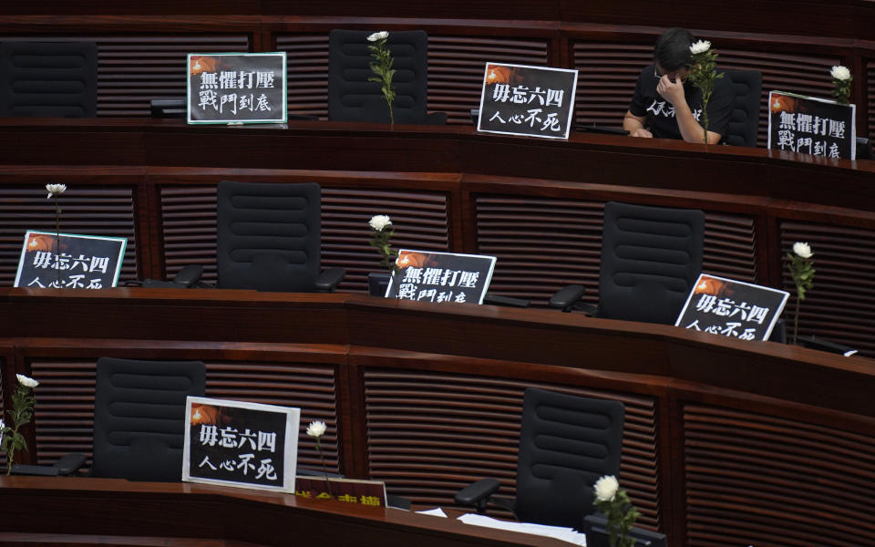 Pan-democratic legislator Andrew Wan reacts next to a flower and placards reading "Always remember the 4th of June, the hearts of the people will never die" after he observed one minute of silence for the 31st anniversary of Tiananmen crackdown before a Legislative Council meeting to debate national anthem bill in Hong Kong, Thursday, June 4, 2020. On the anniversary of Tiananmen crackdown, Hong Kong continued debating a contentious law that makes it illegal to insult or abuse the Chinese national anthem. (AP Photo/Vincent Yu)