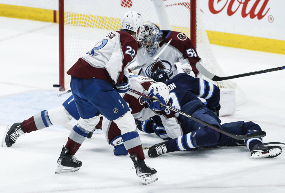 A shot by Winnipeg Jets center David Gustafsson (19) goes off Colorado Avalanche goaltender Ivan Prosvetov (50) as Avalanche's Caleb Jones (82) and Fredrik Olofsson (22) defend during second-period NHL hockey game action in Winnipeg, Manitoba, Saturday, Dec. 16, 2023. (John Woods/The Canadian Press via AP)