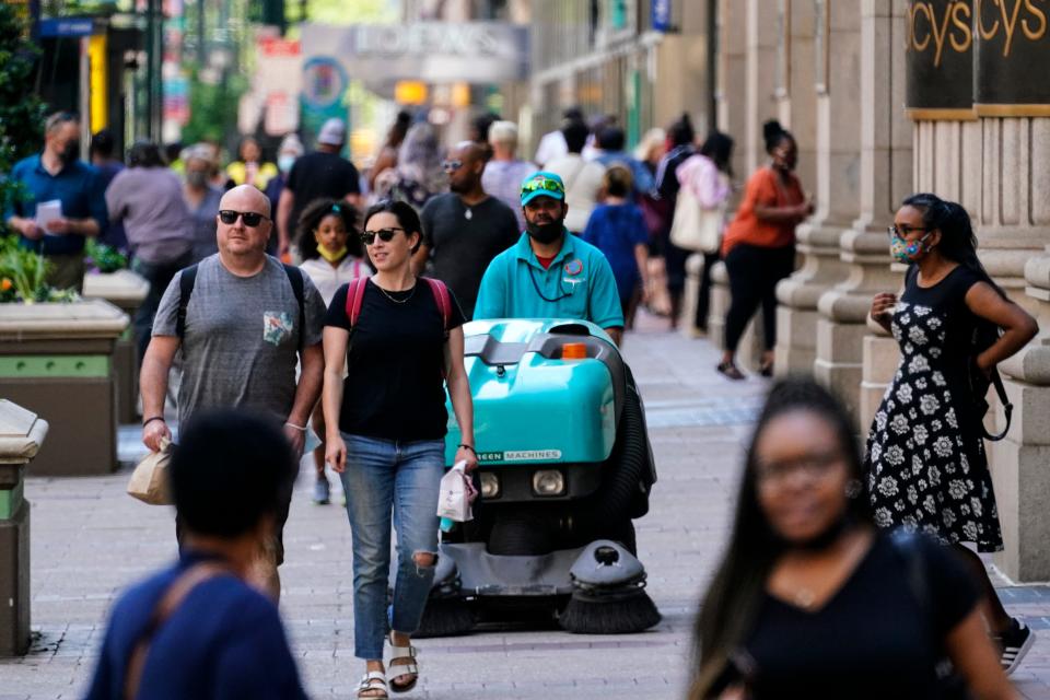 People, some without masks, walk along Market Street in Philadelphia, Friday, May 21, 2021.