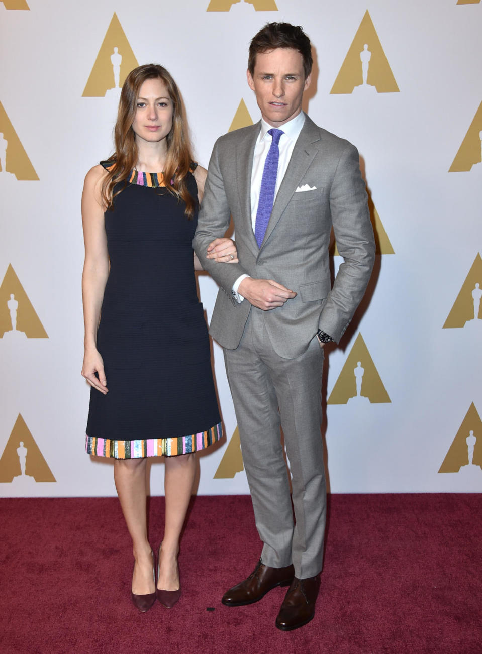 Eddie Redmayne in a gray suit with a purple tie with his pregnant wife, Hannah Bagshawe, at the 88th Annual Academy Awards nominee luncheon on February 8, 2016 in Beverly Hills, California.