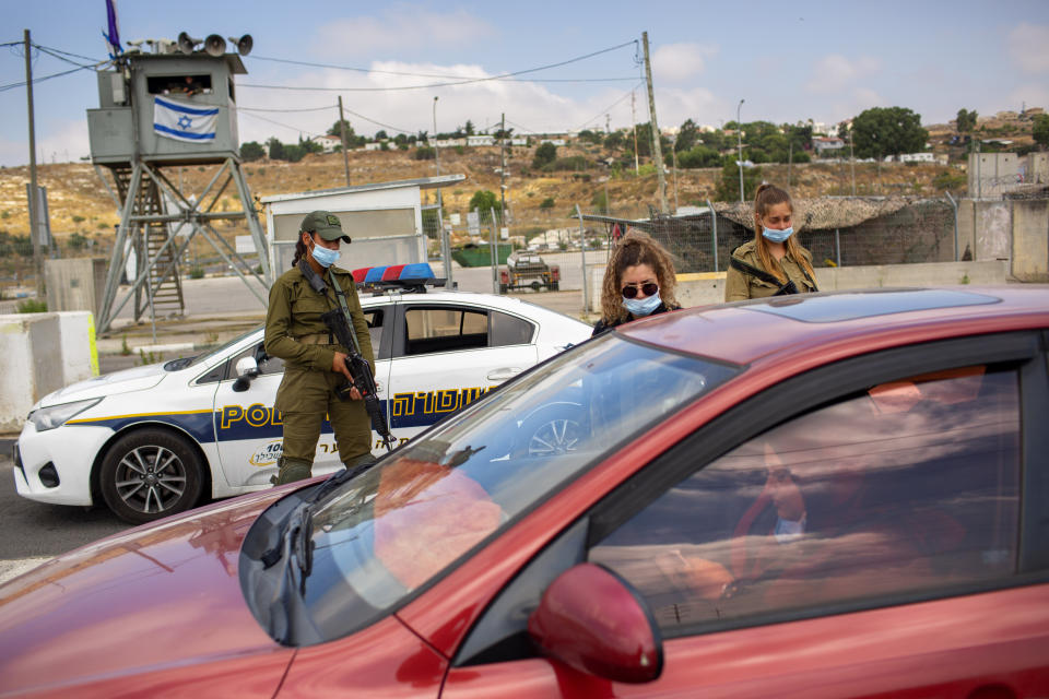 FILE - In this Tuesday, June 30, 2020 file photo, Israeli soldiers check the ID of a Palestinian woman at the Tapuach junction checkpoint next to the West Bank city of Nablus. Israel's premier human rights group has begun describing both Israel and its control of the Palestinian territories as a single "apartheid" regime, using an explosive term that the Israeli government and its supporters vehemently reject. (AP Photo/Oded Balilty, File)