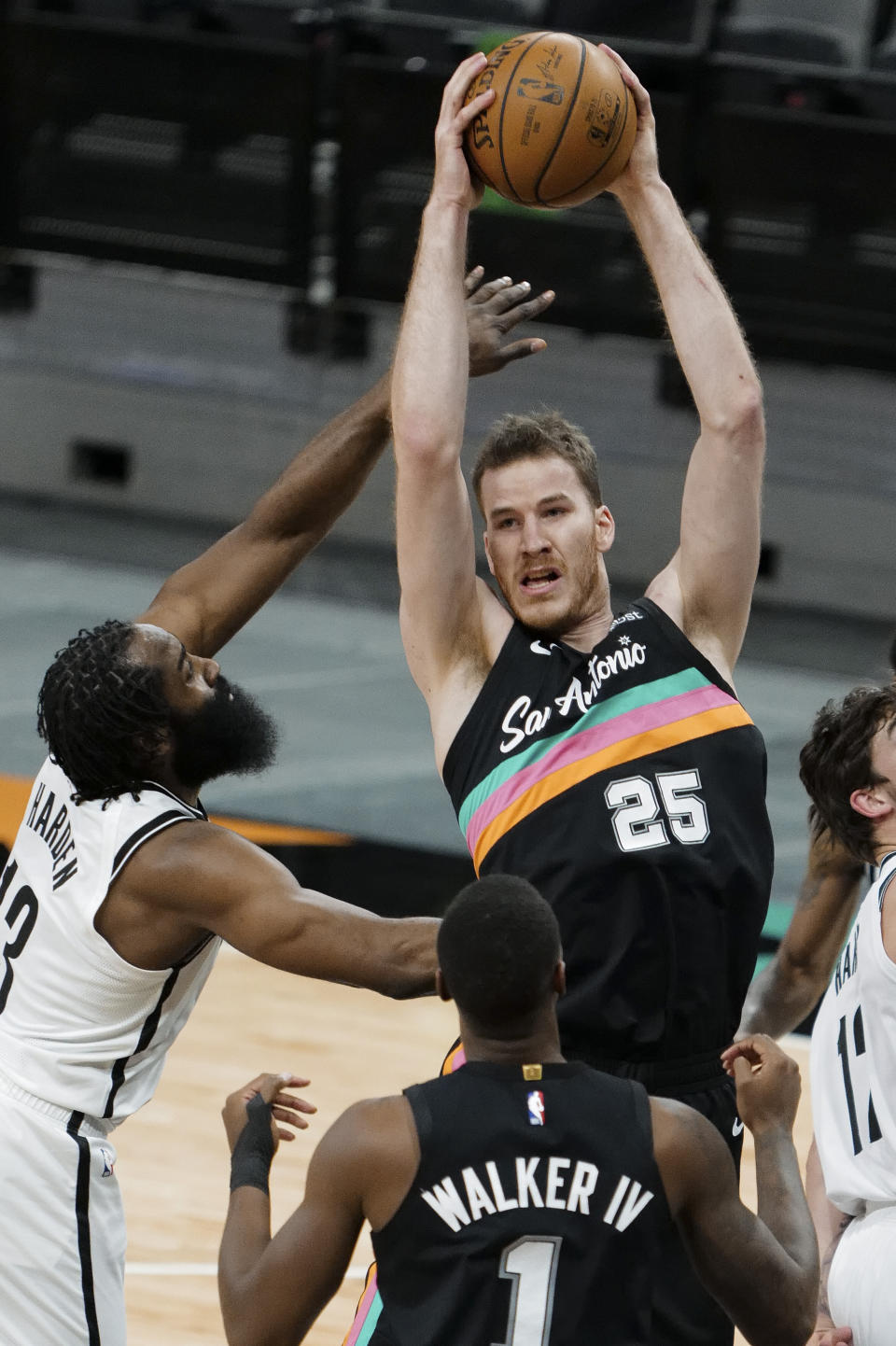 San Antonio Spurs' Jakob Poeltl (25) fights for the rebound against Brooklyn Nets' James Harden, left, during the first half of an NBA basketball game, Monday, March 1, 2021, in San Antonio. (AP Photo/Darren Abate)