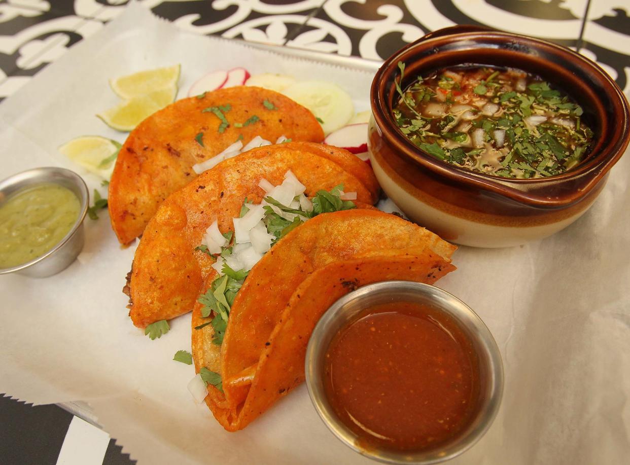 Birria tacos, featuring stewed beef cooked with chili peppers, is served with a bowl of Birria Consome at Amigos Taqueria in Stow.