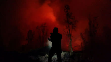 A person is silhouetted against the light from lava in Pahoa, Hawaii, U.S., May 17, 2018 in this picture obtained from social media on May 18, 2018. KRIS BURMEISTER/via REUTERS