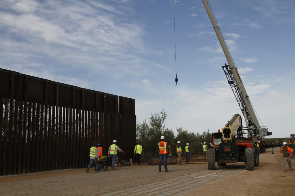 Workers break ground on new border wall construction about 20 miles west of Santa Teresa, New Mexico, Aug. 23, 2019. The wall visible on the left was built in 2018 with money allocated by Congress, while the new construction is funded by money reallocated from Department of Defense funding. (AP Photo/Cedar Attanasio)