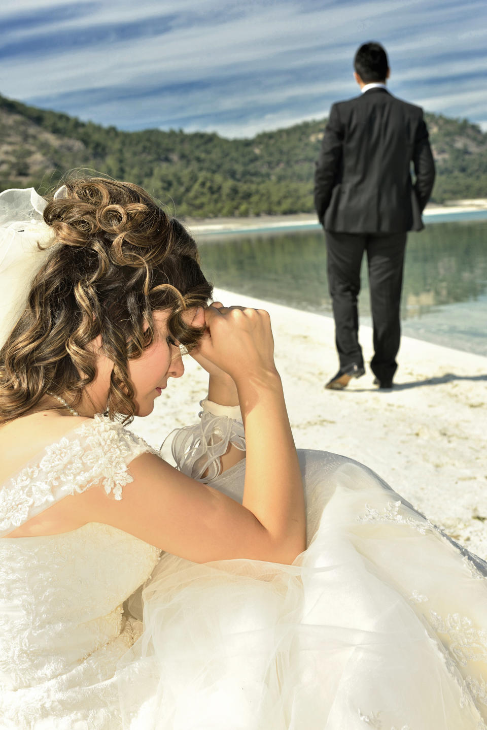 A groom walks away from his bride on the beach