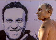 A man wearing a Vladimir Putin mask takes part in a demonstration for prisoned Alexei Navalny, poster at left, in Geneva, Switzerland Tuesday, June 15, 2021. US President Joe Biden and Russia President Vladimir Putin will meet for talks in Geneva on Wednesday. (AP Photo/Michael Probst)