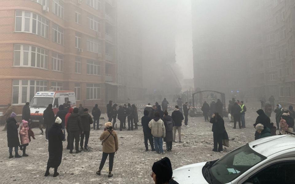 People walk near a smoking high-rise apartment building after a Russian missile attack on December 29, 2023 in Odesa, Ukraine.