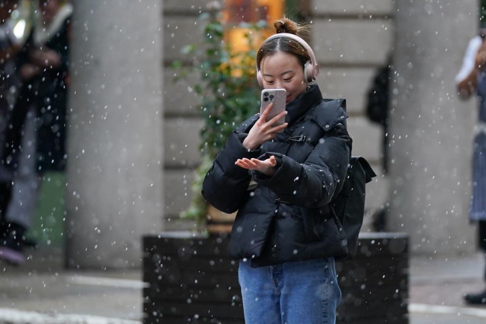 A person on her mobile phone capturing images of the snow in Covent Garden in London (PA)