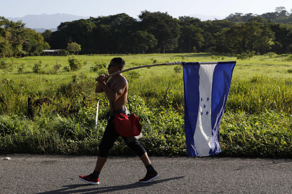 FILE - In this Oct. 25, 2018 file photo, a Honduran migrant carries his national flag as he walks north as part of a thousands strong caravan trying to reach the U.S., still over 1000 miles away, near Mapastepec, Mexico. Fleeing violence, poverty, corruption and chaos, thousands of Hondurans continue to flee despite the dangers and uncertain prospects even if they make it to the U.S. (AP Photo/Rebecca Blackwell, File)