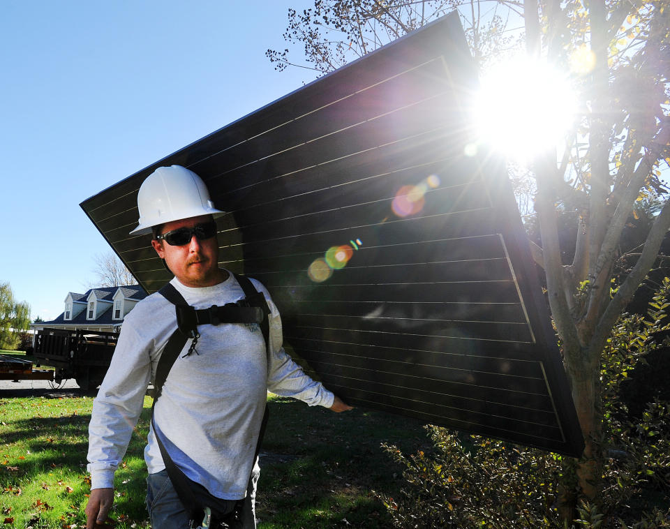 Sean Morris of Clean Energy USA, located in Rehoboth Beach, carries a solar panel to be installed at a home. Milton officials are mulling over a proposed ordinance, which would either exempt solar panels and other green energy installments from property taxes or tax them at a lower rate.