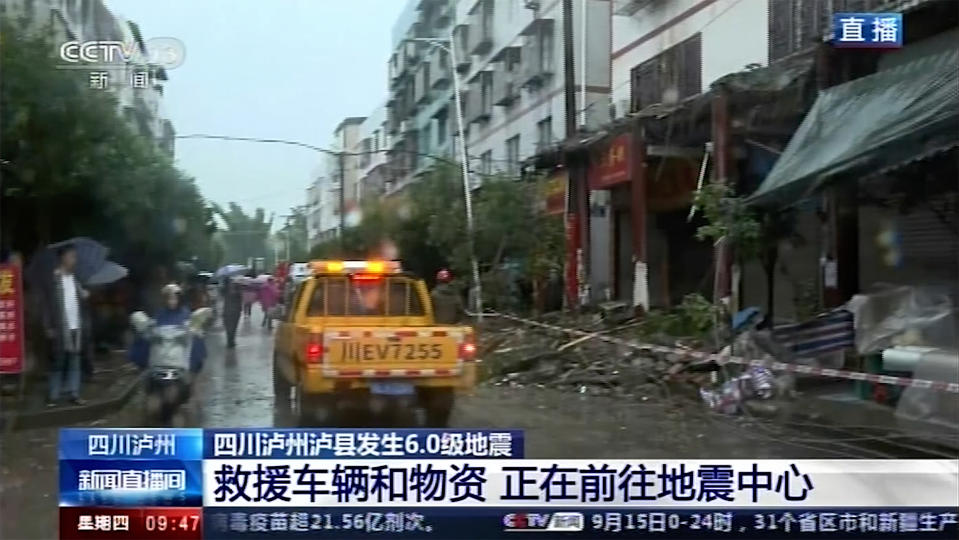 In this image made from video run by China's CCTV, people walk by damaged shophouses following an earthquake in Luxian County, southwest China's Sichuan Province, Thursday, Sept. 16, 2021. Rescue work was underway following the magnitude-6.0 earthquake. (CCTV via AP)