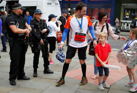 Armed police officers stand on duty as participants in a fun run walk past in central Manchester, Britain, May 28, 2017. REUTERS/Phil Noble